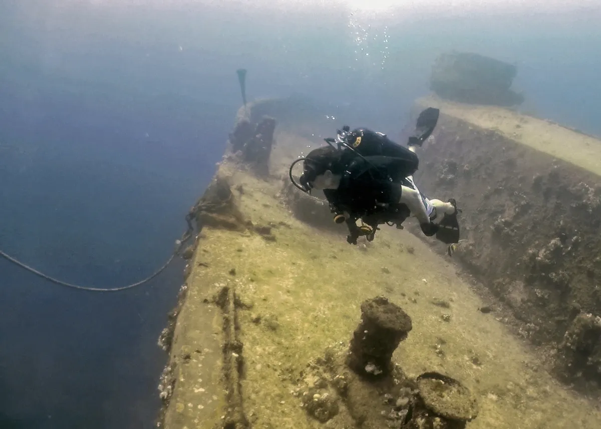 Diver swimming over a sunken shipwreck hull in clear water, the kind of shallow wreck snorkelled on the Korcula shipwreck tour